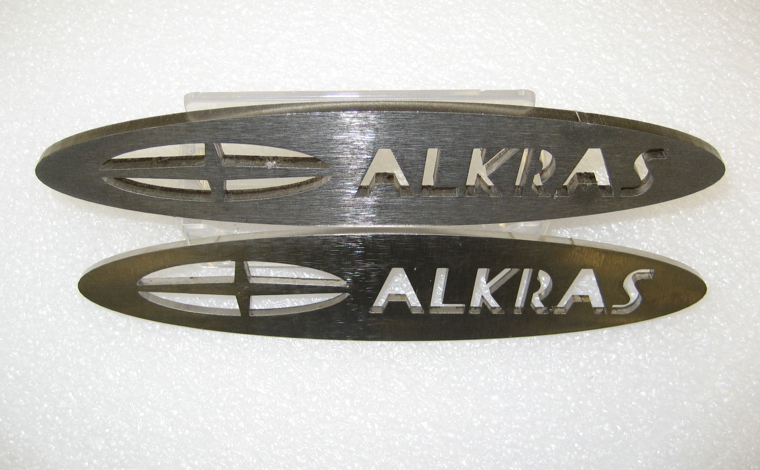 Laser-cut Alkras logo components in stainless steel